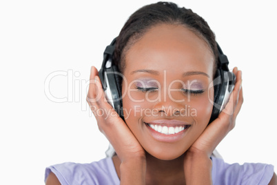 Close up of young woman listening to music with headphones on wh