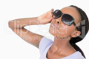 Close up of woman moving her sunglasses against a white backgrou