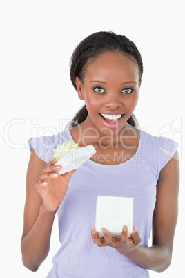 Close up of happy woman opening a present against a white backgr