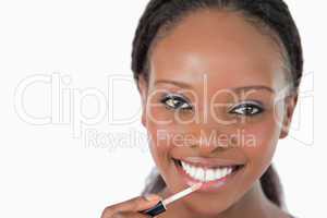 Close up of woman applying lip gloss against a white background