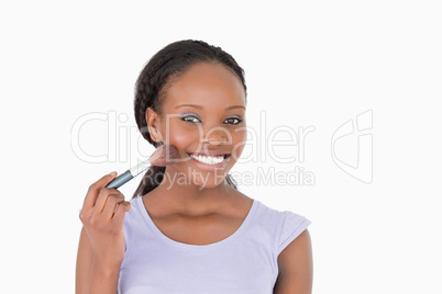 Close up of woman using make-up brush against a white background