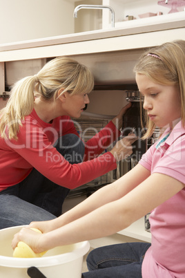 Daughter Helping Mother To Mop Up Leaking Sink