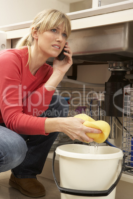 Woman Mopping Up Leaking Sink On Phone To Plumber