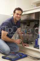 Plumber Working On Sink In Kitchen