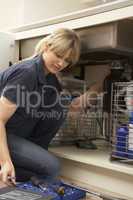Female Plumber Working On Sink In Kitchen