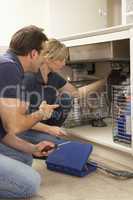 Plumber Teaching Apprentice To Fix Kitchen Sink In Home