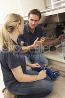 Plumber Teaching Apprentice To Fix Kitchen Sink In Home