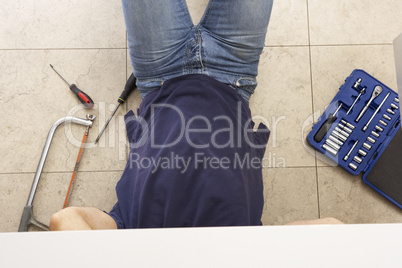 Plumber Working On Sink In Kitchen