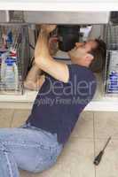 Plumber Working On Sink In Kitchen