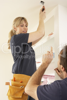 Electrician Teaching Apprentice To Install Light Fitting In Home