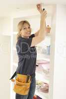 Female Electrician Installing Light Fitting In Home