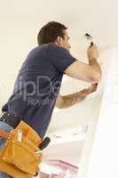 Electrician Installing Light Fitting In Home