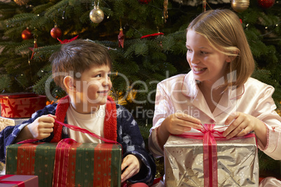 Children Opening Christmas Present In Front Of Tree