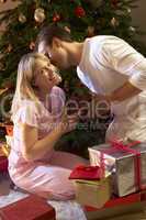 Couple Exchanging Presents In Front Of Tree