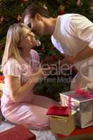 Couple Exchanging Presents In Front Of Tree