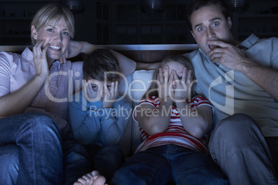 Family Watching Scary Programme On TV Sitting On Sofa Together