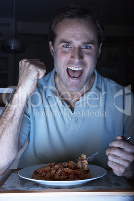 Man Enjoying Meal And Cheering Whilst Watching TV