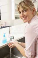 Woman Washing Hands At Kitchen Sink