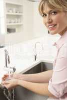 Woman Washing Hands At Kitchen Sink