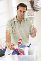 Bored Man Cleaning Light Fitting With Feather Duster