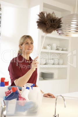 Cleaner Working In Domestic Kitchen With Feather Duster