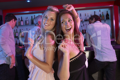 Two Young Women Having Fun In Busy Bar