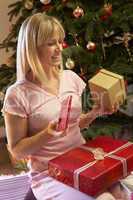 Woman Opening Christmas Present In Front Of Tree