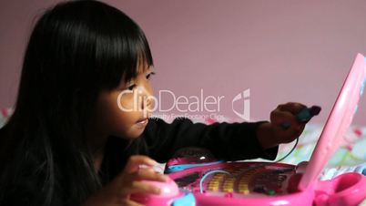 Little Girl Playing On Pink Laptop Computer