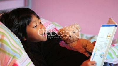 Little Asian Girl Reads Story Book To Teddy Bear