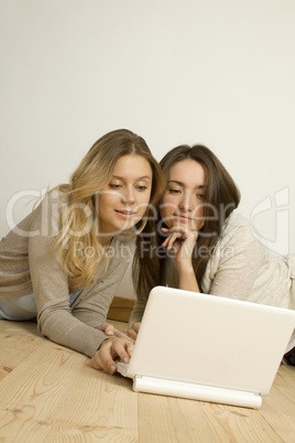 Two attractive friends at home with laptop