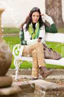 Autumn park bench young woman hold phone