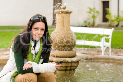 Autumn park fountain young woman hold phone