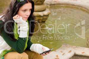 Autumn park fountain young woman hold phone