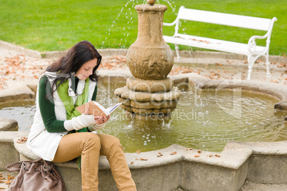 Autumn park fountain young woman read book