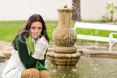 Autumn park young woman sit on fountain