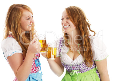 zwei glückliche frauen in dirndl beim anstossen mit bier