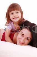 A portrait of a mother and her baby girl lying on the bed and sm