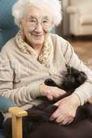 Senior Woman Relaxing In Chair At Home With Pet Cat