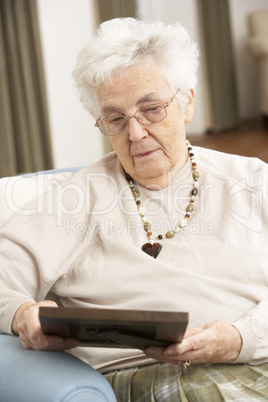Senior Woman Looking At Photograph In Frame