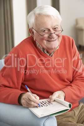 Senior Man Relaxing In Chair At Home Completing Crossword