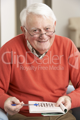 Senior Man Relaxing In Chair At Home Completing Crossword