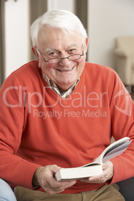 Senior Man Relaxing In Chair At Home Reading Book