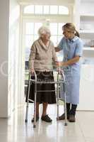 Carer Helping Elderly Senior Woman Using Walking Frame