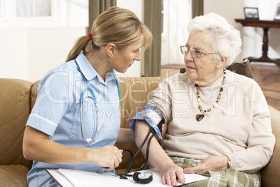 Senior Woman Ihaving Blood Pressure Taken By Health Visitor At H