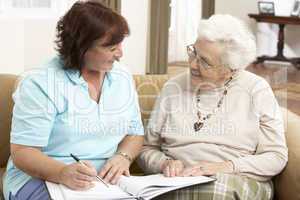 Senior Woman In Discussion With Health Visitor At Home