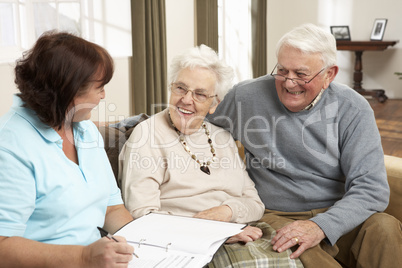 Senior Couple In Discussion With Health Visitor At Home