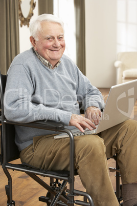 Disabled Senior Man Sitting In Wheelchair Using Laptop