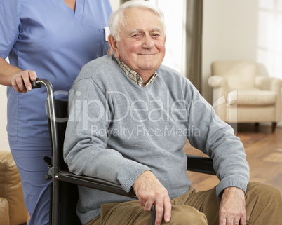 Disabled Senior Man Sitting In Wheelchair With Carer Behind