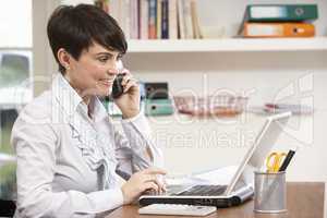 Woman Working From Home Using Laptop On Phone