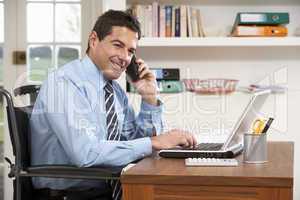 Man Working From Home Using Laptop On Phone